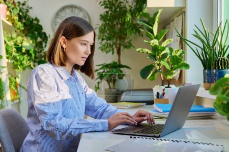 Photo for Young woman typing on laptop computer at home. Female freelancer, an employee working remotely, university student studying online preparing for exams. Technology youth training education work concept - Royalty Free Image