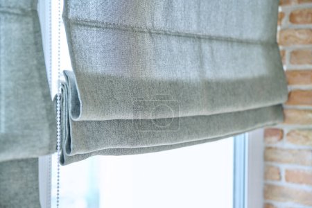 Primer plano de persianas romanas con tela de lino gris. Diseño, protección funcional, diseño moderno de la decoración de la ventana de moda en el hogar