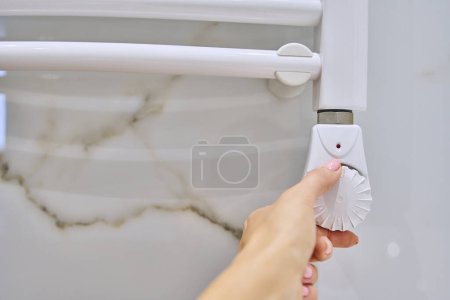 Téléchargez les photos : Radiateur de chauffage mural électrique, thermostat de température main sur main, douche de bain, porte-serviettes chauffant - en image libre de droit