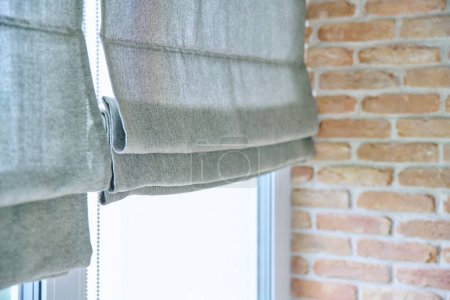 Close-up of roman blinds with gray linen fabric. Design, functional protection, fashionable modern window decoration design at home
