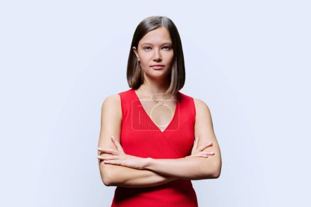 Téléchargez les photos : Portrait de jeune femme confiante en rouge sur fond de studio blanc. Femme à la mode avec des bras croisés regardant la caméra. Affaires, travail, services, éducation, beauté de la mode - en image libre de droit