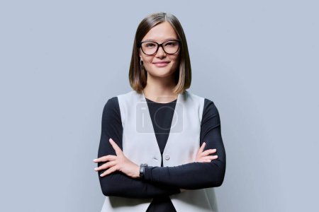 Photo for Young confident trendy smiling woman in eyeglasses with crossed arms looking at camera on gray studio background. Beauty, business, work entrepreneurship business expert owner agent concept - Royalty Free Image