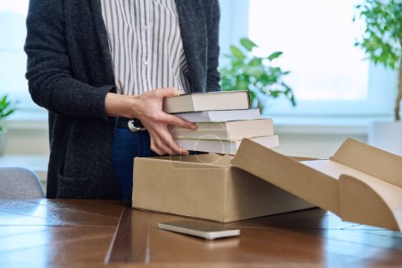 Photo for Close-up of womans hands unpacking cardboard box with new books, online purchase from internet book store, postal delivery, online shopping, books literature concept - Royalty Free Image