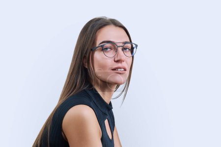 Téléchargez les photos : Portrait headshot de jeune belle femme dans des lunettes à la mode sur fond de studio blanc. Gros plan du visage d'une femme à la mode regardant la caméra. Beauté, mode, style - en image libre de droit