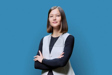 Photo for Young confident trendy serious woman with crossed arms looking at camera on blue studio background. Beauty, business, work entrepreneurship business expert owner agent concept - Royalty Free Image