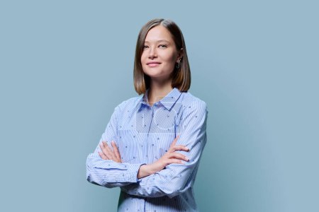 Photo for Portrait of confident successful young woman with crossed arms looking at camera on blue studio background. 20s age people, youth, work, education, fashion, lifestyle concept - Royalty Free Image
