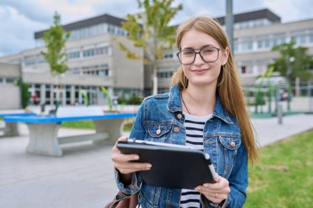 Photo for Girl student teenager outdoor near school building. Smiling teenage female with backpack digital tablet posing looking at camera. Adolescence, education, learning concept - Royalty Free Image