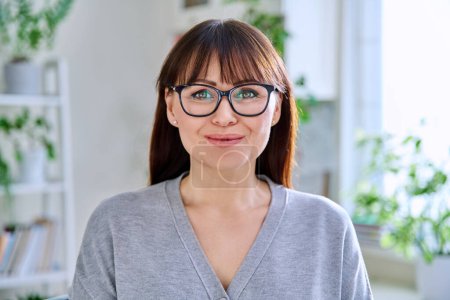 Téléchargez les photos : Portrait en gros plan d'une femme souriante d'âge moyen portant des lunettes à la maison. Âge positif de la femme heureuse des années 40, concept de style de vie joyeux émotions - en image libre de droit