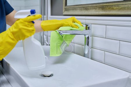 Foto de Primer plano del fregadero de limpieza con grifo en el baño, manos femeninas en guantes protectores de goma con detergente de limpieza y trapo profesional. Limpieza de la casa limpieza limpieza concepto de servicio de limpieza - Imagen libre de derechos