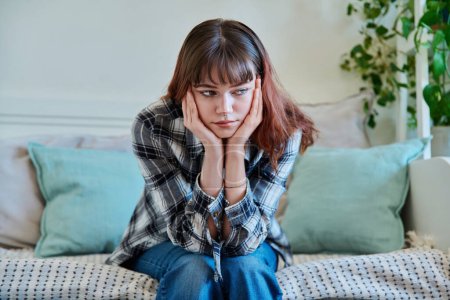 Photo for Upset sad lonely young woman sitting on couch at home. Disappointed female 19-20 years old, girl college student in sadness. Depression, stress, mental difficulties, youth concept - Royalty Free Image