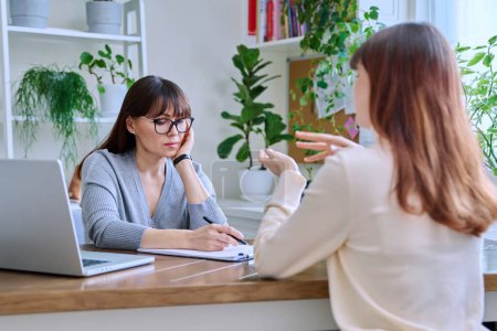Photo for Middle-aged female psychologist, psychotherapist, counselor, social worker working with young woman patient. Psychology therapy professional help consultation treatment support mental health concept - Royalty Free Image