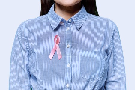 Photo for Woman with pink ribbon on her chest symbolizing International Breast Cancer Day, on white studio background. Solidarity, patient support, health care, treatment, medicine, world cancer day - Royalty Free Image