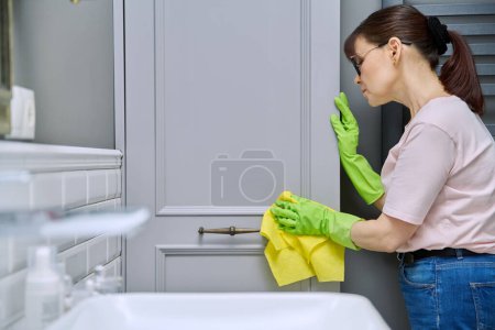 Photo for Woman is cleaning, wiping dust from furniture with soft cloth, polishing the wooden surfaces of furniture. Housekeeping, housework, housecleaning, cleaning service concept - Royalty Free Image
