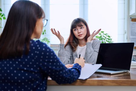 Photo for Teenage girl college student at therapy meeting with mental health professional social worker psychologist counselor sitting together in office. Psychology, psychotherapy, mental assistance support - Royalty Free Image