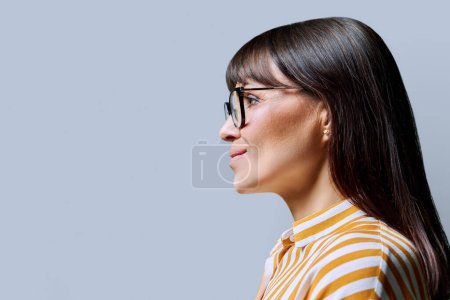 Photo for Profile view of middle aged smiling woman looking forward, gray studio background, copy space for advertising image text. Mature business confident successful female. Marketing sales services, people - Royalty Free Image