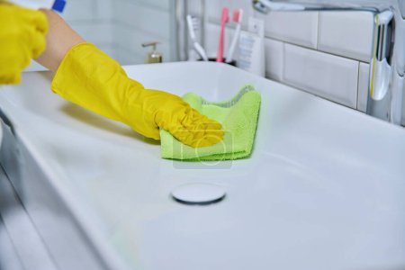 Photo for Close-up of cleaning sink with faucet in bathroom, female hands in rubber protective gloves with cleaning detergent and professional rag. Housekeeping housework housecleaning cleaning service concept - Royalty Free Image