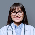 Headshot portrait smiling friendly middle-aged female doctor in white lab coat with stethoscope, looking at camera on gray studio background. Healthcare, medicine, staff, treatment, medical services