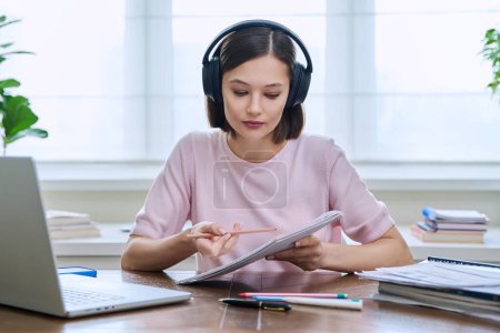 Young female college university student in headphones talking studying using laptop computer for video chat conference call sitting at home. Internet online remote lessons webinars education training