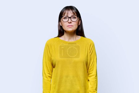 Photo for Portrait of a serious mature confident woman on a white studio background. Middle aged female in yellow, glasses looking at camera, lifestyle, health, work, 40s people concept - Royalty Free Image