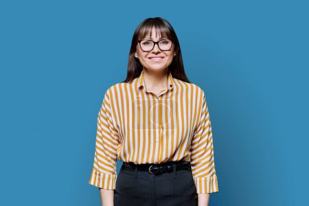 Photo for Portrait of confident smiling happy middle aged businesswoman on blue background. Positive female with glasses looking at camera. 40s professional, beauty health lifestyle work business services - Royalty Free Image