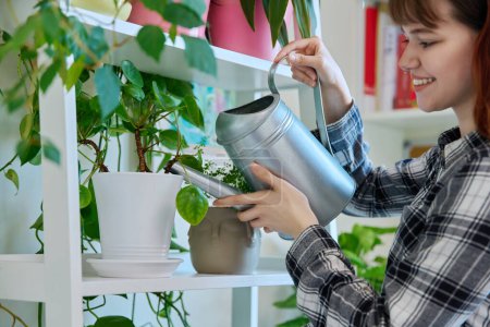 Téléchargez les photos : Jeune femme arrosant des pots avec des plantes de l'arrosoir, intérieur de la maison. Aménagement paysager, tendances écologiques, concept lifestyle - en image libre de droit