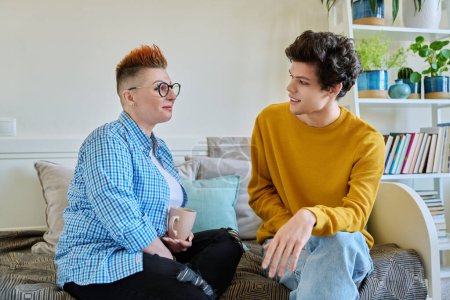 Photo for Happy middle-aged mother and son 19-20 years old, talking sitting together on couch at home. Mothers day, lifestyle family communication parenthood tenderness, positive relationship, two generation - Royalty Free Image