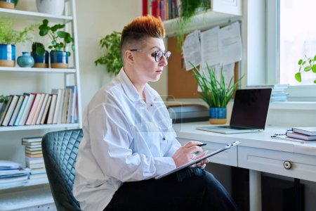 Photo for Portrait of serious female psychotherapist with clipboard at workplace in office. Professional mental therapist counselor psychologist social worker taking notes. Health care services, treatment - Royalty Free Image