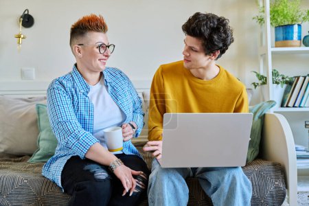 Photo for Middle-aged mother and son 19-20 years old sitting together on couch at home looking at laptop screen talking. Lifestyle family communication parenthood tenderness positive relationship two generation - Royalty Free Image