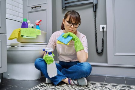 Photo for Tired woman sitting on the floor after cleaning bathroom, toilet. Routine house cleaning, home hygiene, housecleaning service, housekeeping, housework - Royalty Free Image