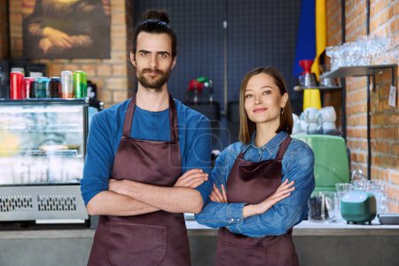 Photo for Small business team portrait of confident successful colleagues partners young man woman in aprons posing looking at camera at workplace in restaurant coffee shop cafeteria. Partnership teamwork work - Royalty Free Image
