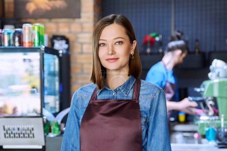 Photo for Confident successful young woman service worker in apron looking at camera in restaurant cafeteria coffee shop pastry shop. Small business, staff, occupation, entrepreneur owner, work concept - Royalty Free Image