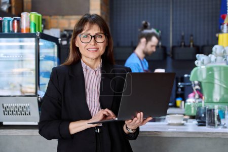Photo for Portrait of confident business woman accountant financier lawyer small business owner. Successful middle-aged female using laptop computer looking at camera background coffee shop cafeteria restaurant - Royalty Free Image