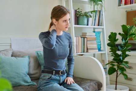Junge Teenager leiden unter Nackenschmerzen, wenn sie zu Hause auf der Couch sitzen. Symptome des Bewegungsapparates, neurologische Erkrankungen, akute Infektionskrankheiten