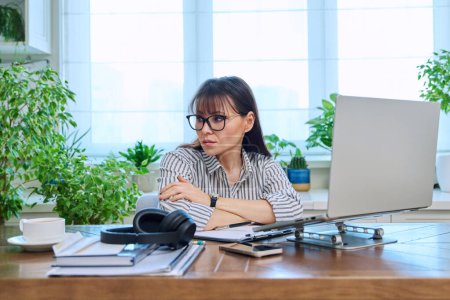 Photo for Sad upset tired businesswoman sitting at workplace with computer laptop in home office. Difficulties, problems in business, work - Royalty Free Image