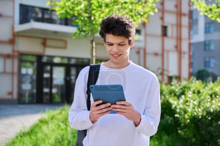 Photo for Young handsome guy college student using digital tablet outdoor, educational building background. Education, technology, training, 19,20 years age youth concept - Royalty Free Image