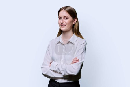 Photo for Portrait of young teenage serious female in white shirt with crossed arms on white studio background. Confident beautiful girl college student looking at camera - Royalty Free Image