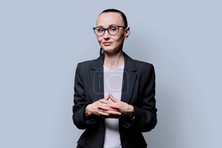 Photo for Portrait of thinking serious 30s business woman on grey studio background. Confident female in glasses, suit looking at camera. Business work teaching job career people concept - Royalty Free Image