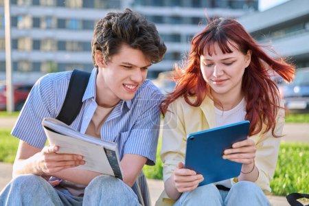 Photo for Teenage college students guy and girl talking, using digital tablet, sitting outdoor, urban modern city. Youth 19-20 years old, education, technologies, lifestyle, friendship concept - Royalty Free Image