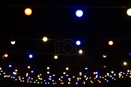 Photo for A view from below of a lot of small light bulbs, a festive garland illuminating the night sky - Royalty Free Image
