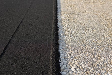 New paved road edge and curb. The texture of new asphalt and crushed stone