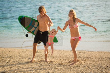 Téléchargez les photos : Jeunes et beaux parents jouant avec sa fille sur la plage - en image libre de droit
