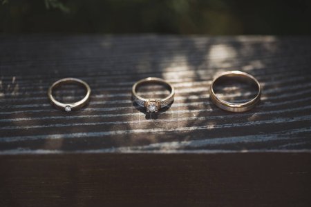 Three rings on wooden background. Engagement ring and two wedding bands on wooden table. White gold wedding jewelry.