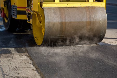 Téléchargez les photos : Un rouleau de route compactant l'asphalte - en image libre de droit