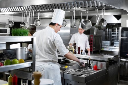 Moderne Küche. Köche bereiten Gerichte auf dem Herd in der Küche eines Restaurants oder Hotels zu