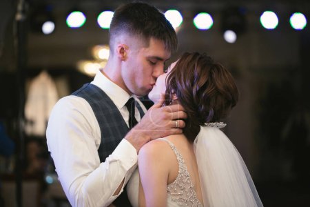 Téléchargez les photos : Joyeux couple de mariage effectue la première danse dans un restaurant, câlin et baiser. - en image libre de droit