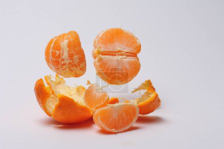 Téléchargez les photos : Les mandarines pelées sur fond blanc flottent sur leur écorce. photographie studio. - en image libre de droit