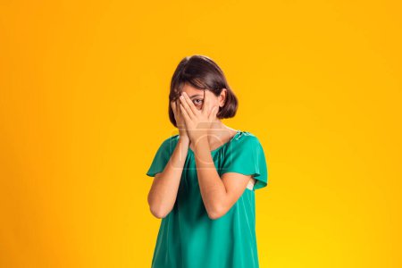Photo for Kid girl feeling fear, closed her eyes with hands over yellow background. Frustration concept - Royalty Free Image