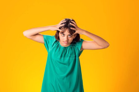 Photo for Sad kid girl holding her head over yellow background. Frustration concept - Royalty Free Image