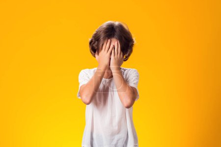 Photo for Kid girl feeling fear, closed her eyes with hands over yellow background. Frustration concept - Royalty Free Image