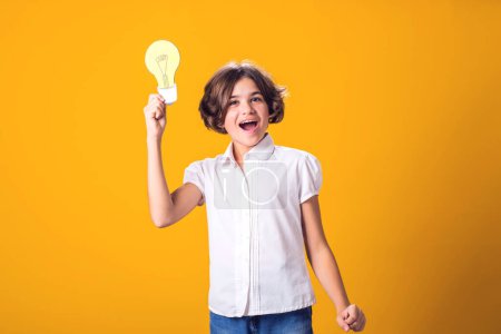 Téléchargez les photos : Petite fille tenant une ampoule en papier. Succès, motivation, vainqueur, génie, concept d'idée - en image libre de droit